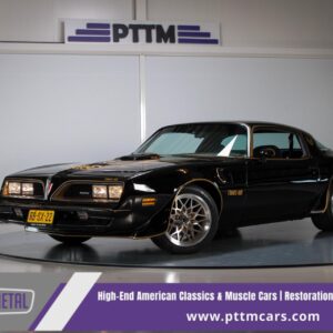 Full driver's side profile of the restored black 1978 Pontiac Trans Am WS6 showing the Bandit gold side striping, new 17-inch honeycomb wheels, and Flowmaster exhaust tips