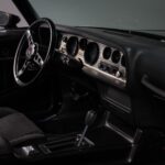 Full dashboard of the black 1978 Pontiac Trans Am WS6 showing the rebuilt interior with factory-style gauge cluster, retro-fit Vintage Air heating and defroster controls, and new trim